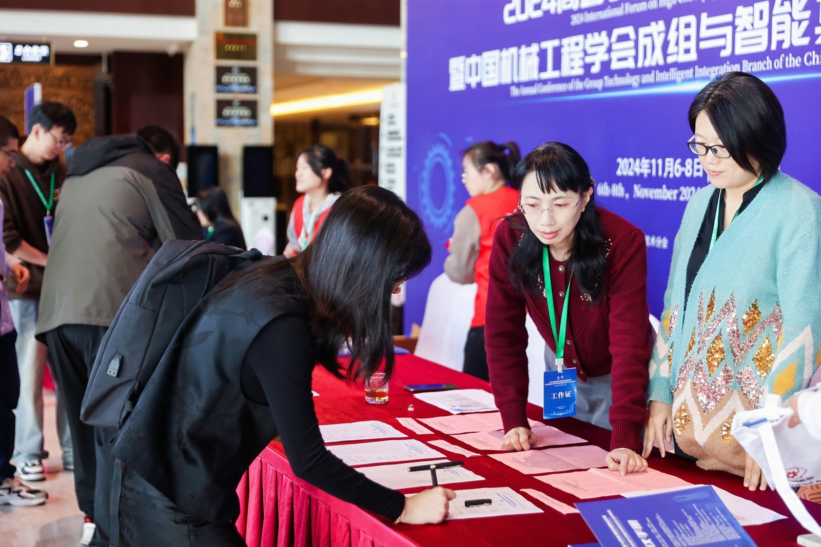 签到现场实拍，参会者在签到台完成注册登记，会务人员现场提供会议咨询服务